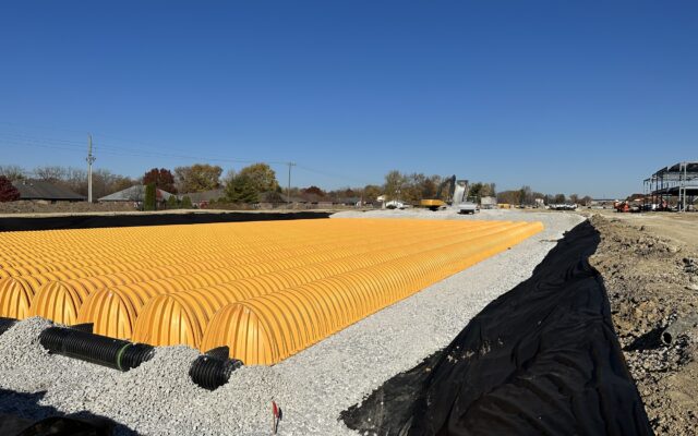 Yellow stormwater chambers on gravel at a construction site.
