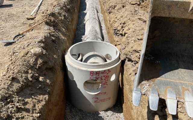 Storm drain inlet in trench, connected pipe, equipment and gravel.