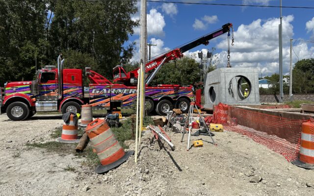 Tow truck crane lifts concrete structure at construction site.