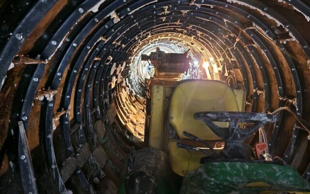 Partially built tunnel with metal supports, equipment, and cables.