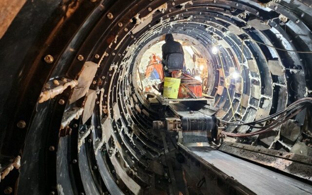 Worker stands in illuminated, under-construction metal tunnel.