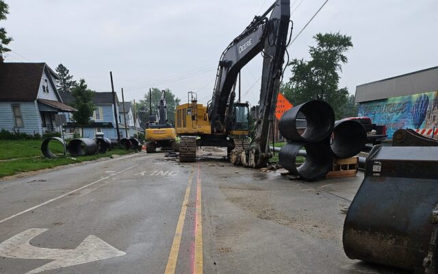 Excavators and pipes block a closed street under construction.