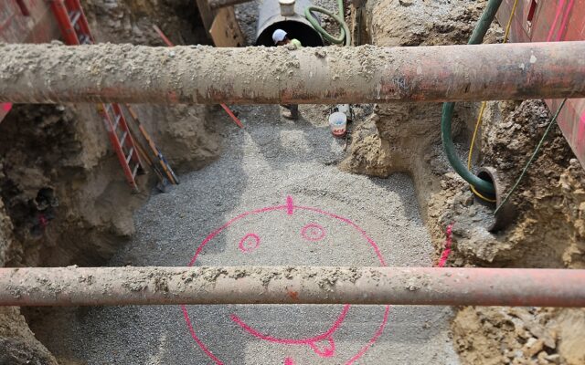 Excavation site with ladders, gravel, and a big pink smiley face.