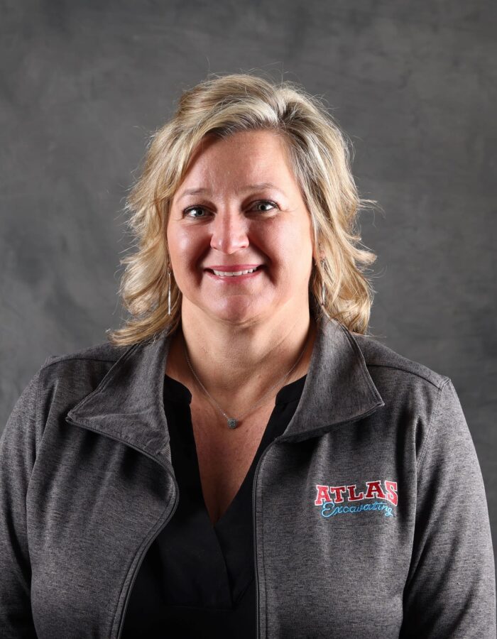 Blonde woman in gray ATLAS jacket, smiling.