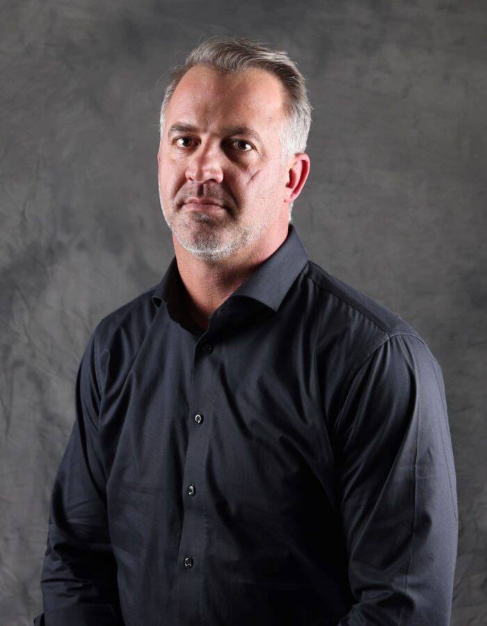 Man with beard, black shirt, gray backdrop.