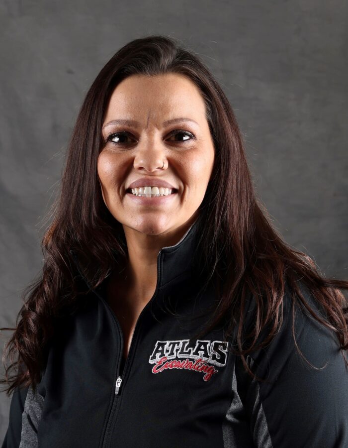 Smiling woman with long brown hair in black Atlas jacket.