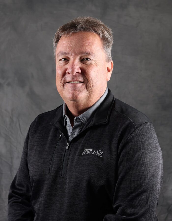 Middle-aged man with gray hair in dark sweater, gray backdrop.