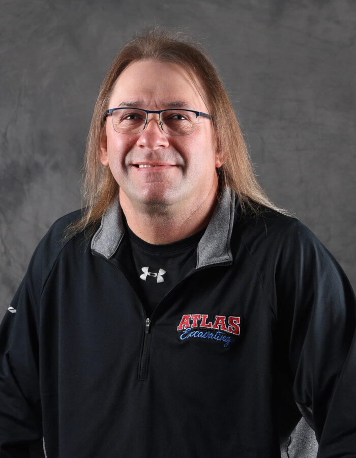 Man with long hair, glasses, black ATLAS jacket.