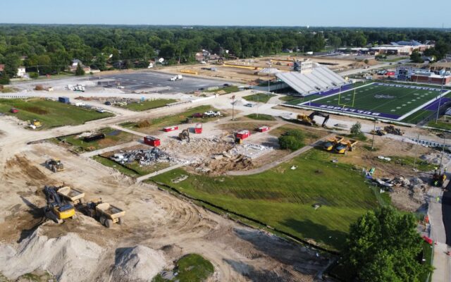 Aerial view of stadium, construction site, machinery, parking lot.