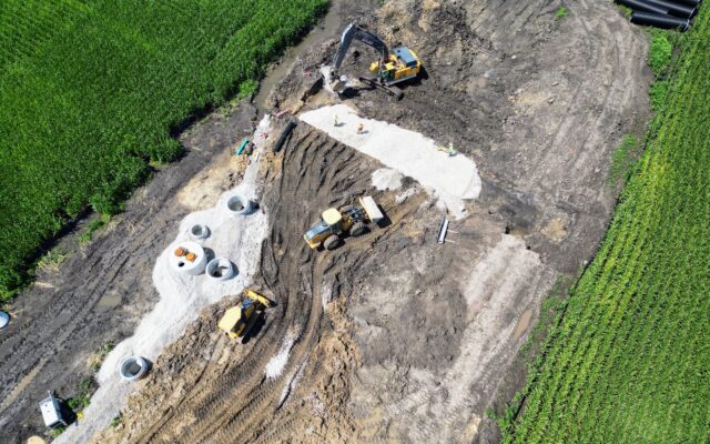 Aerial view: construction site, field, machines, materials, workers.