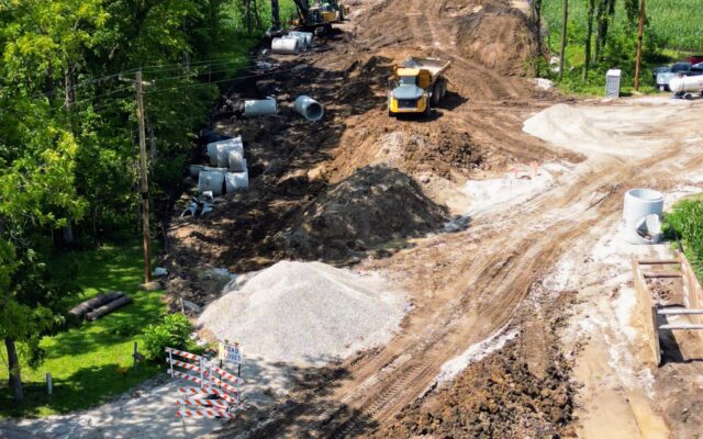Heavy machinery clearing a path in a rural, wooded area.