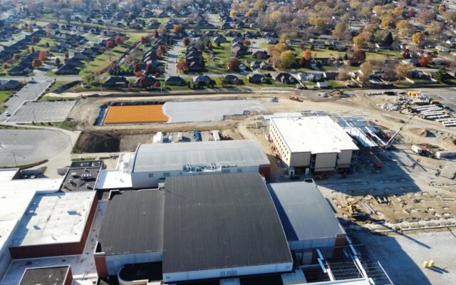 Aerial view: construction site behind large building, autumn houses.