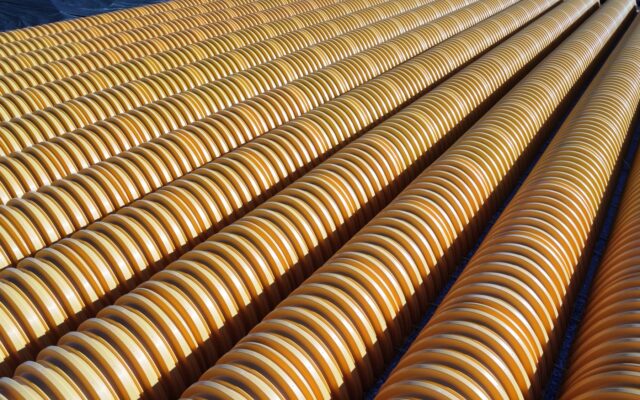 Yellow ridged pipes laid in parallel rows on the ground.