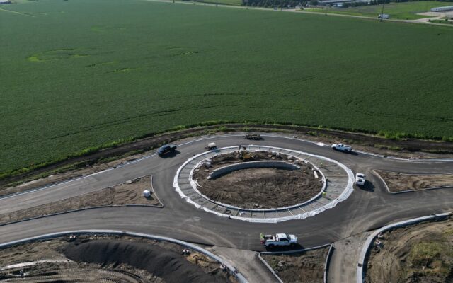 Roundabout construction site amid farmland, vehicles and equipment visible.