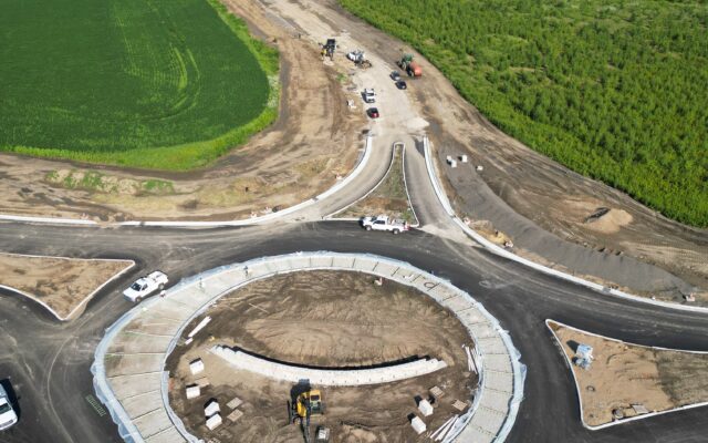 Aerial view of roundabout construction with vehicles and fields.