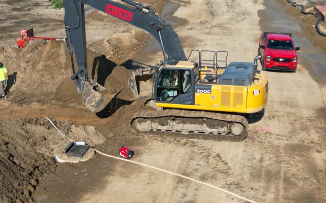 Yellow excavator working near a partially paved road.