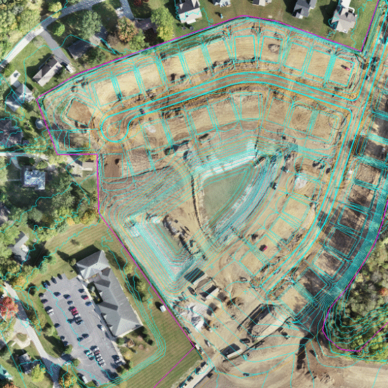 Aerial view of construction site amid homes and parking areas.