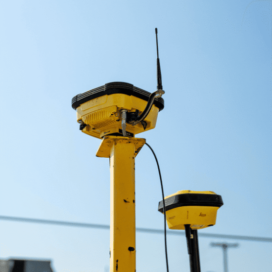 Two yellow GPS units with antennas on poles, blue sky.