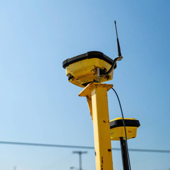 Yellow GPS instrument with antenna on pole, blue sky background.