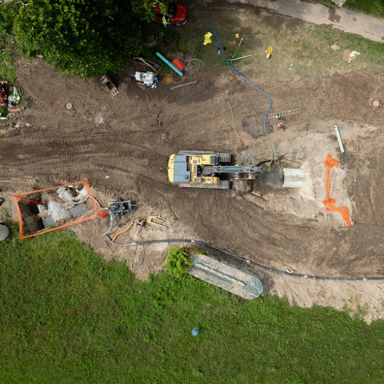 Aerial view of construction site with yellow excavator and equipment.