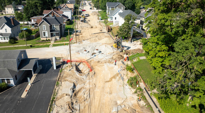 Aerial view of residential street construction with machinery and barriers.