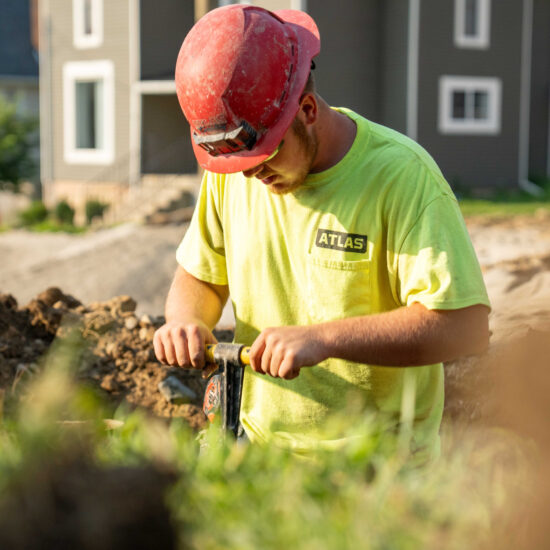 Worker in yellow shirt and red hard hat uses equipment.