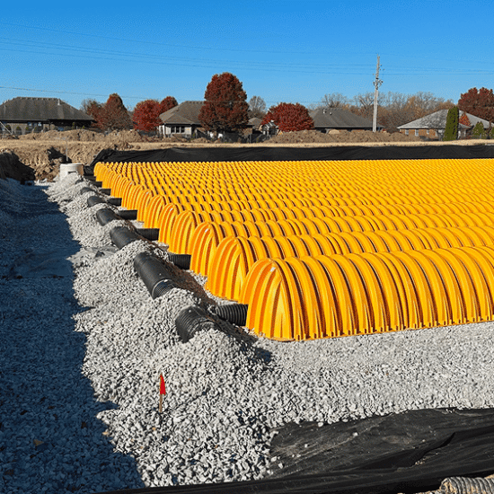 Yellow plastic chambers on gravel at a construction site.