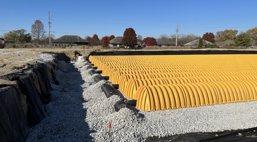 Yellow stormwater chambers on gravel at construction site.