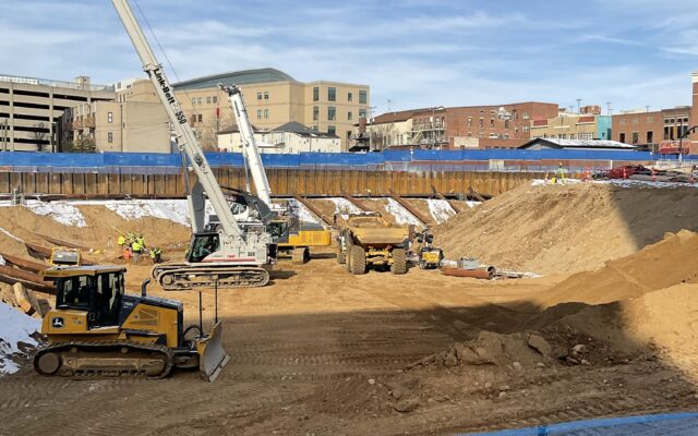 Excavators, cranes, and trucks at a dirt construction site.