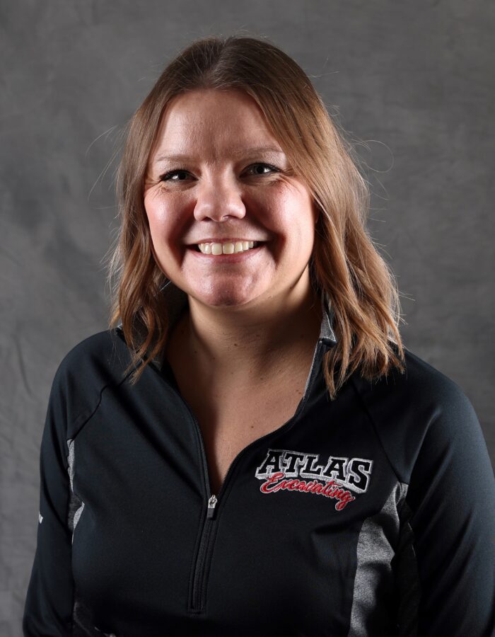 Woman with brown hair smiles, wearing black ATLAS jacket.