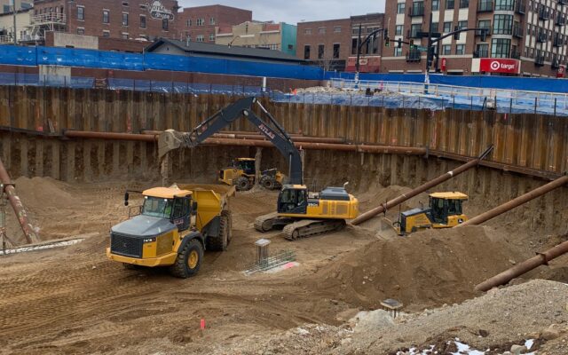 Excavators and dump trucks working in a snowy construction pit.