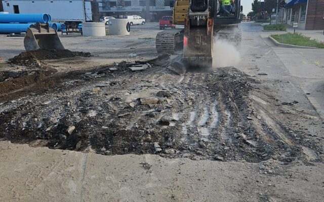 Worker breaks city asphalt with machinery; debris scattered.