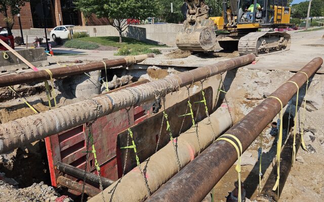 Excavator and trench box at construction site under blue sky.