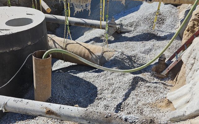 Construction site: exposed pipes, gravel, concrete; materials.