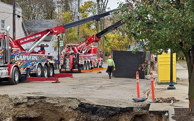 Two large red cranes and a worker by street construction site.