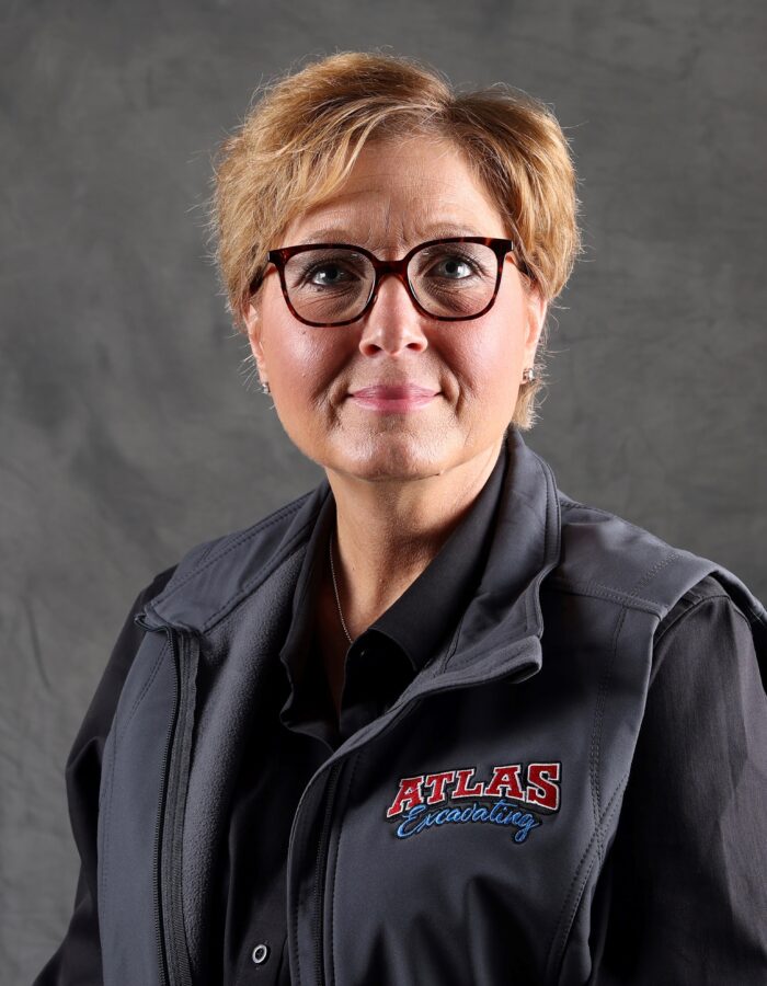 Blonde woman in glasses wears ATLAS Excavating vest and shirt.